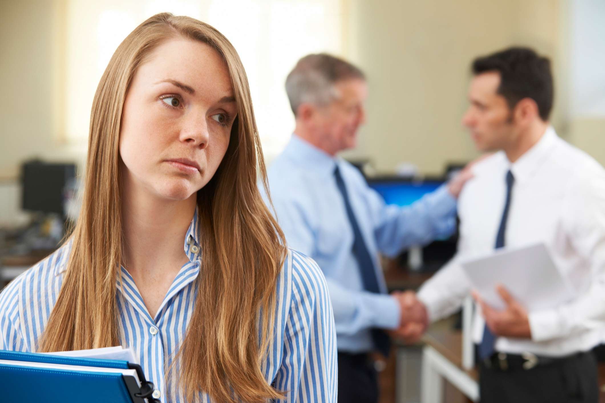 Upset employee watching Upset employee watching coworkers interact asks, what is gaslighting in the workplace?